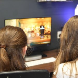 An image of two pupils editing a promotional video on work experience, Their backs are to the camera and in the background you can see the video they are editing