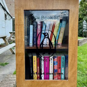 A Little Book Stop with two shelves packed with books outside of Knowle Traditional Sweet Shop