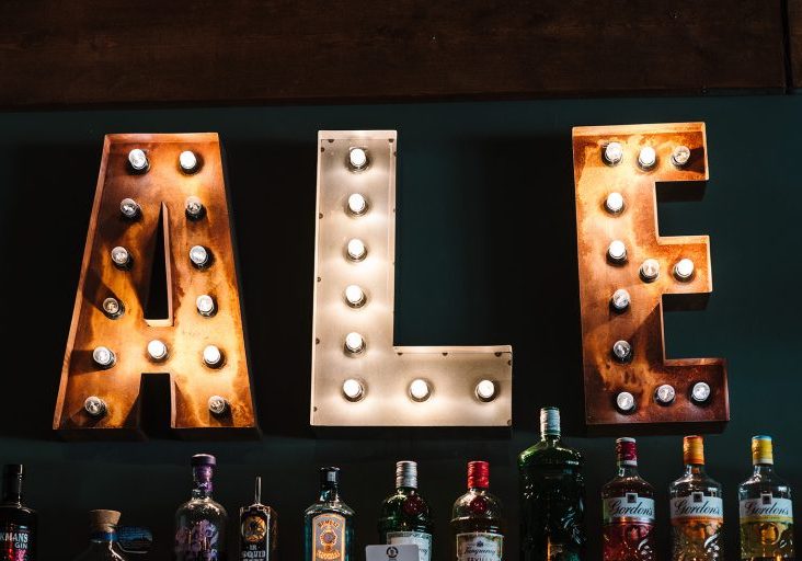 Three individual letters lit up with bulbs spelling the word Ale