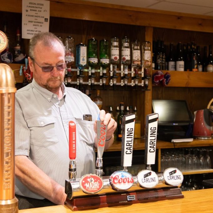 Royal British Legion A man in a shirt is pouring a pint behind the bar of the Royal Legion in Knowle